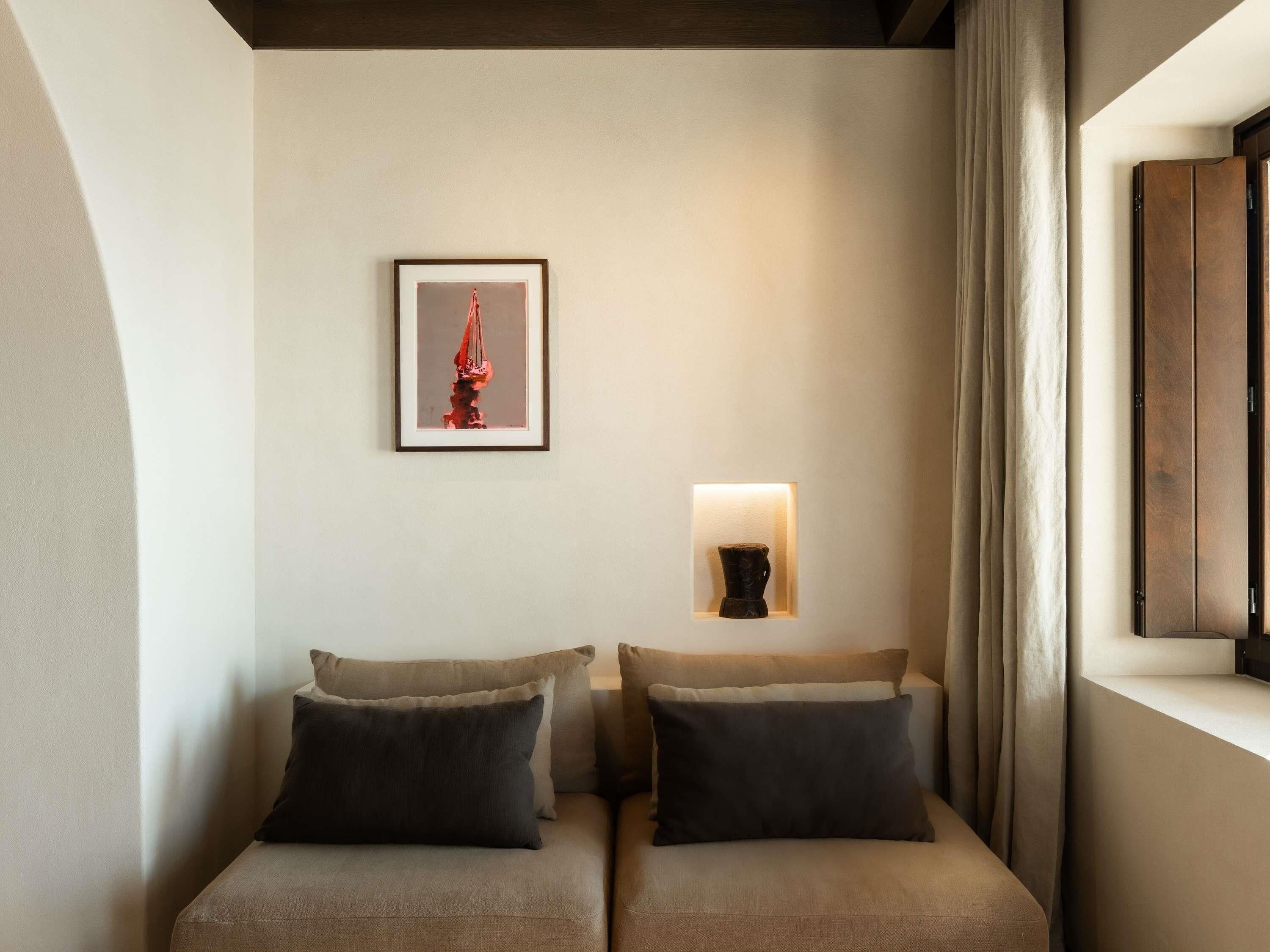 Un coin de pièce avec deux canapés, une œuvre d’art encadrée et un luminaire fixé au mur.