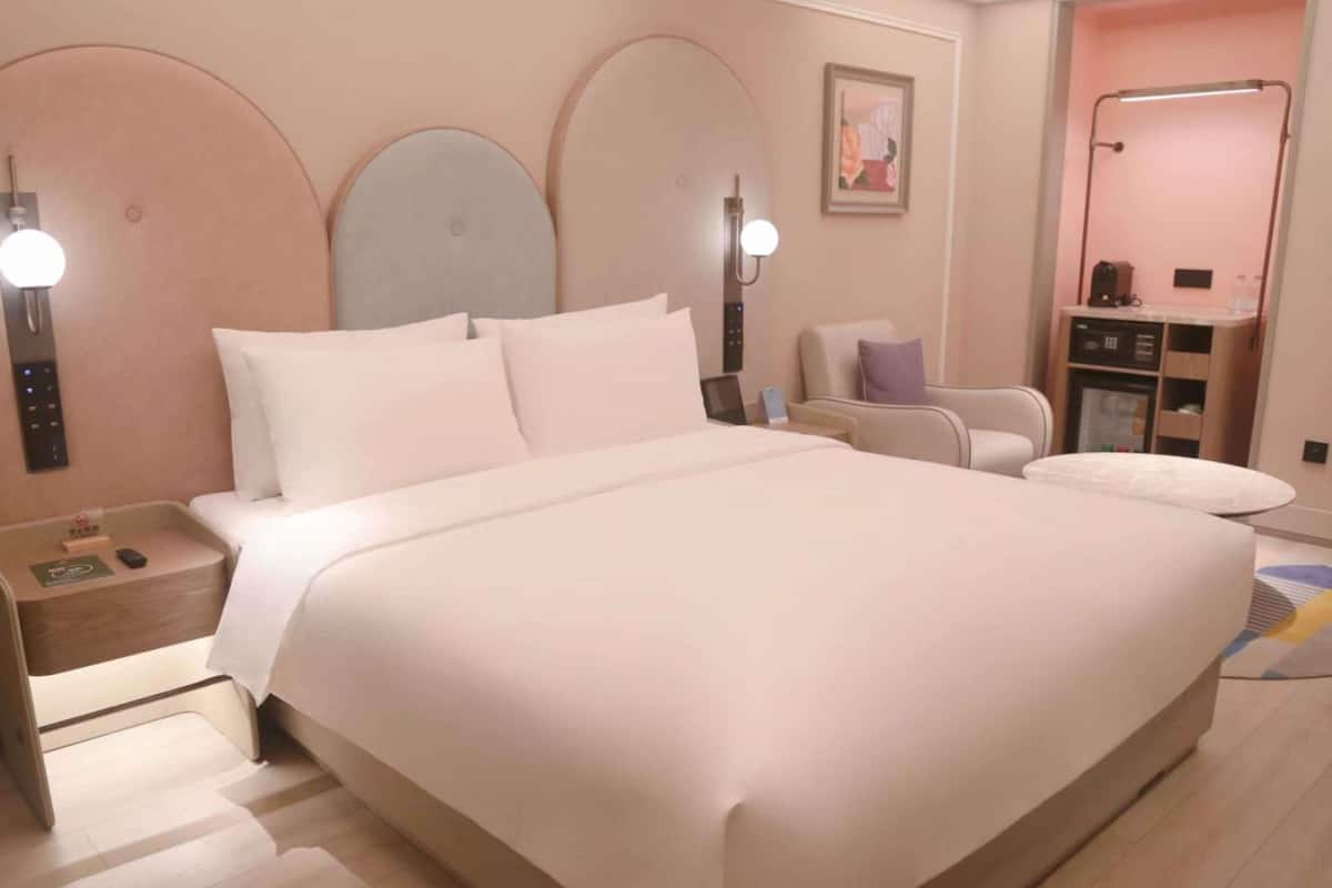 Ein modernes Hotelzimmer mit einem großen Bett, Nachttischen, einer Sitzecke und einem Badezimmer.