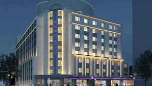Ein modernes Hotel mit einem zentralen Turm und einer schlichten Fassade, mit beleuchteter Beschilderung und einem Glastür-Eingang.