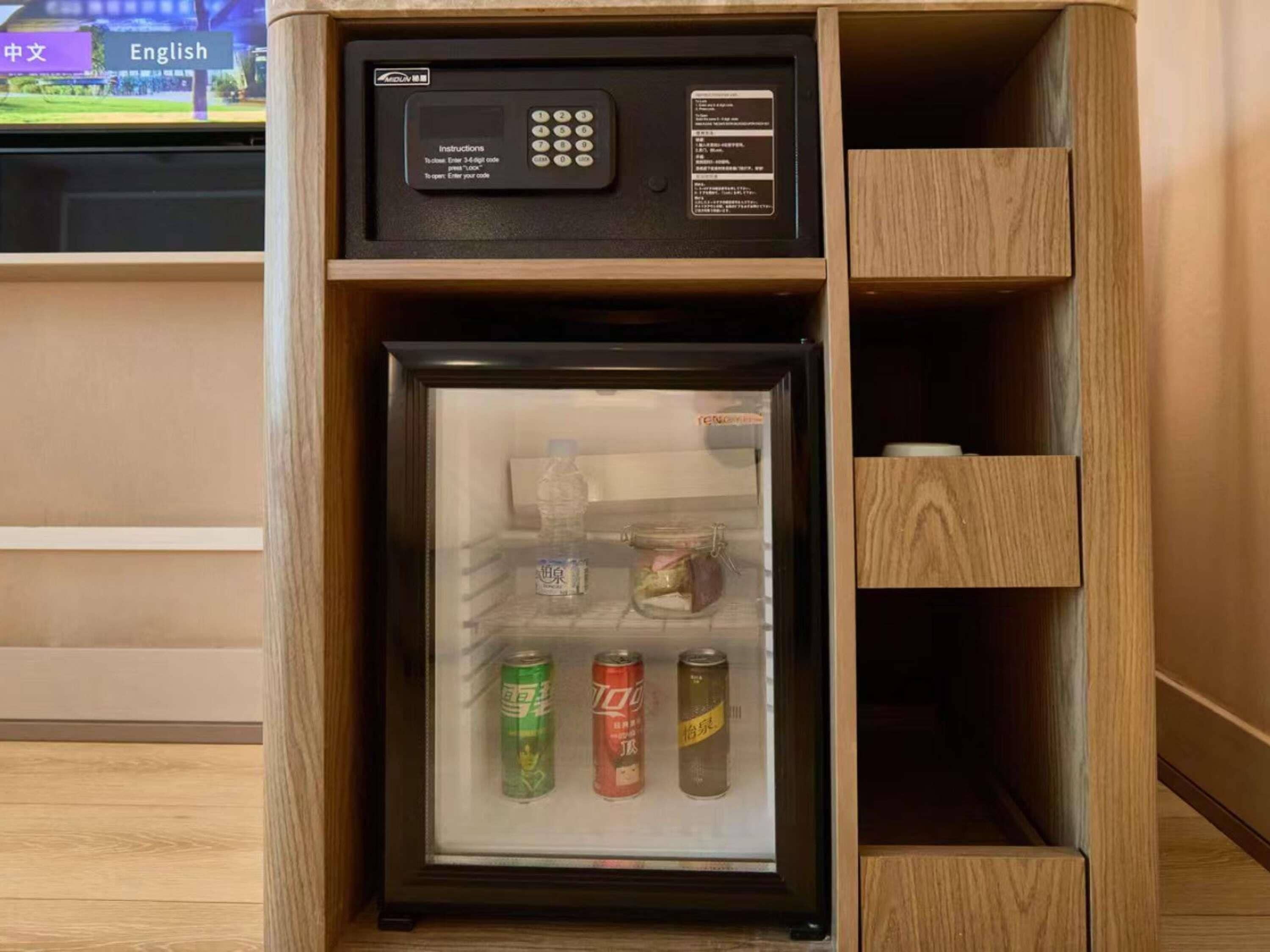 Un refrigerador compacto con candado digital, que contiene bebidas y un tarro.