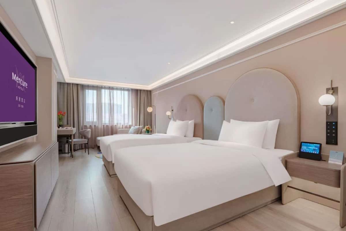 Ein Hotelzimmer mit einem großen Bett, Nachttischen, einem Schreibtisch und einem Fernseher.