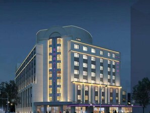 Un hôtel à plusieurs étages, doté d’un design moderne, qui se distingue par son entrée imposante et une série de fenêtres sur sa façade.