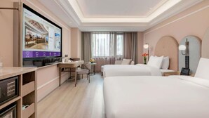 Una camera d'albergo con due letti, una scrivania, una televisione e un minibar.