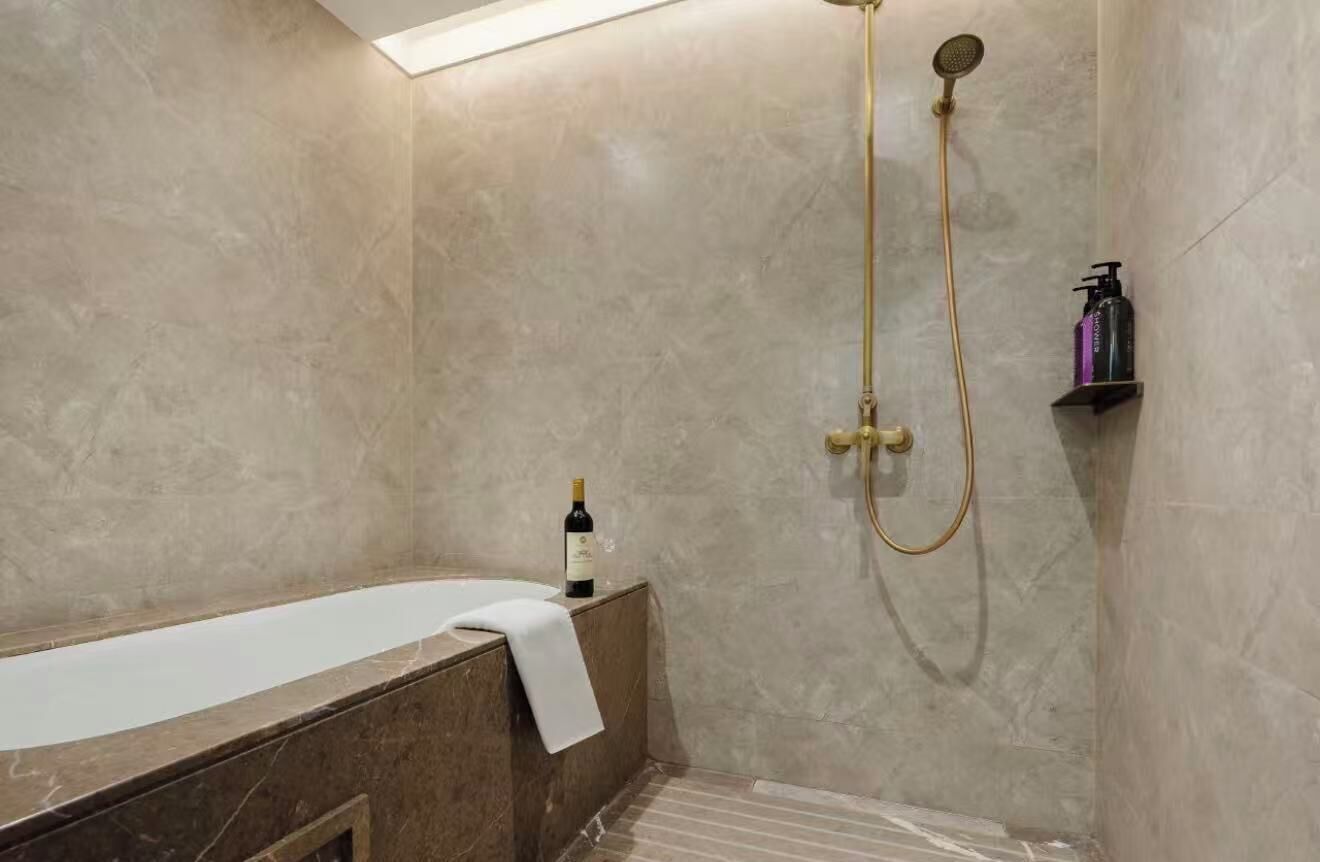 A bathroom with a bathtub, a shower, and a bottle of wine on the side.