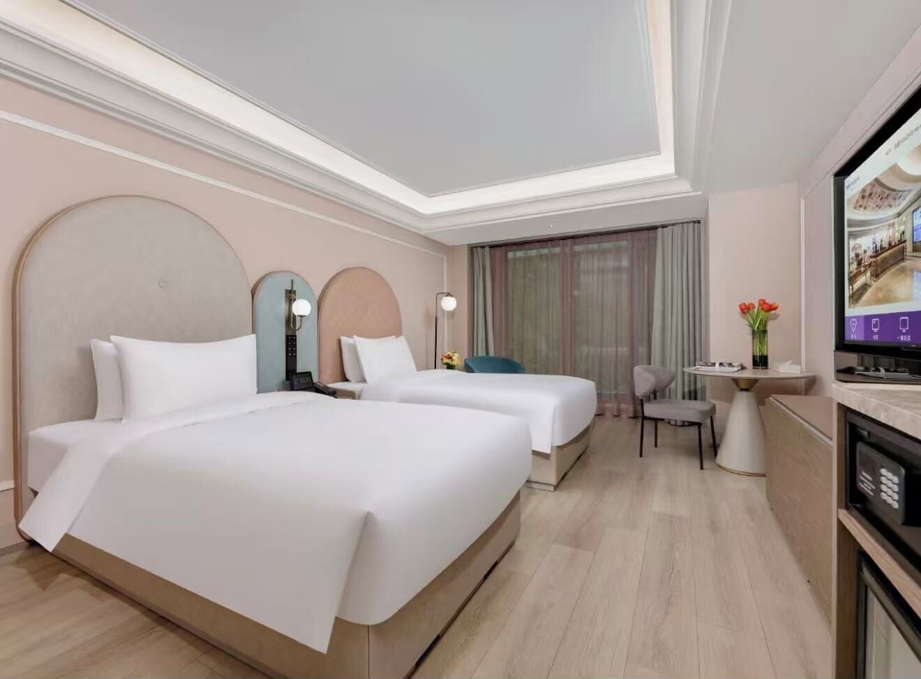 Een hotelkamer met twee bedden, een bureau, een stoel, een televisie en een grote spiegel.