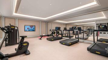Une salle de sport équipée de tapis de course, d’un appareil elliptique et de machines de musculation.