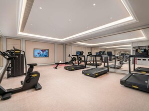 Une salle de sport équipée de tapis de course, d’un appareil elliptique et de machines de musculation.