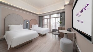 Ett hotellrum med två sängar, ett litet bord, en stol och ett stort fönster.