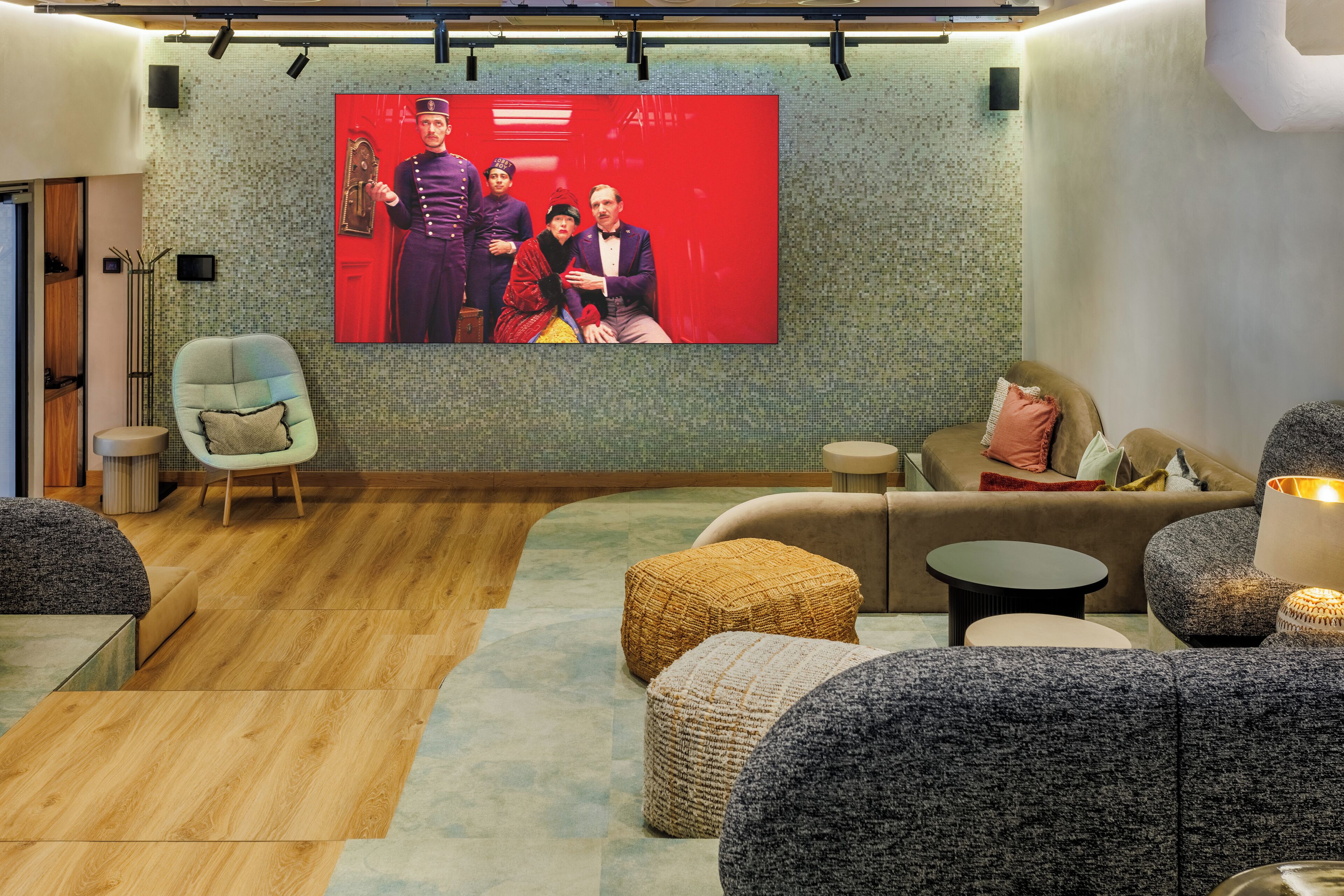 A modern living room with a large flat-screen TV, comfortable seating, and a patterned wall.