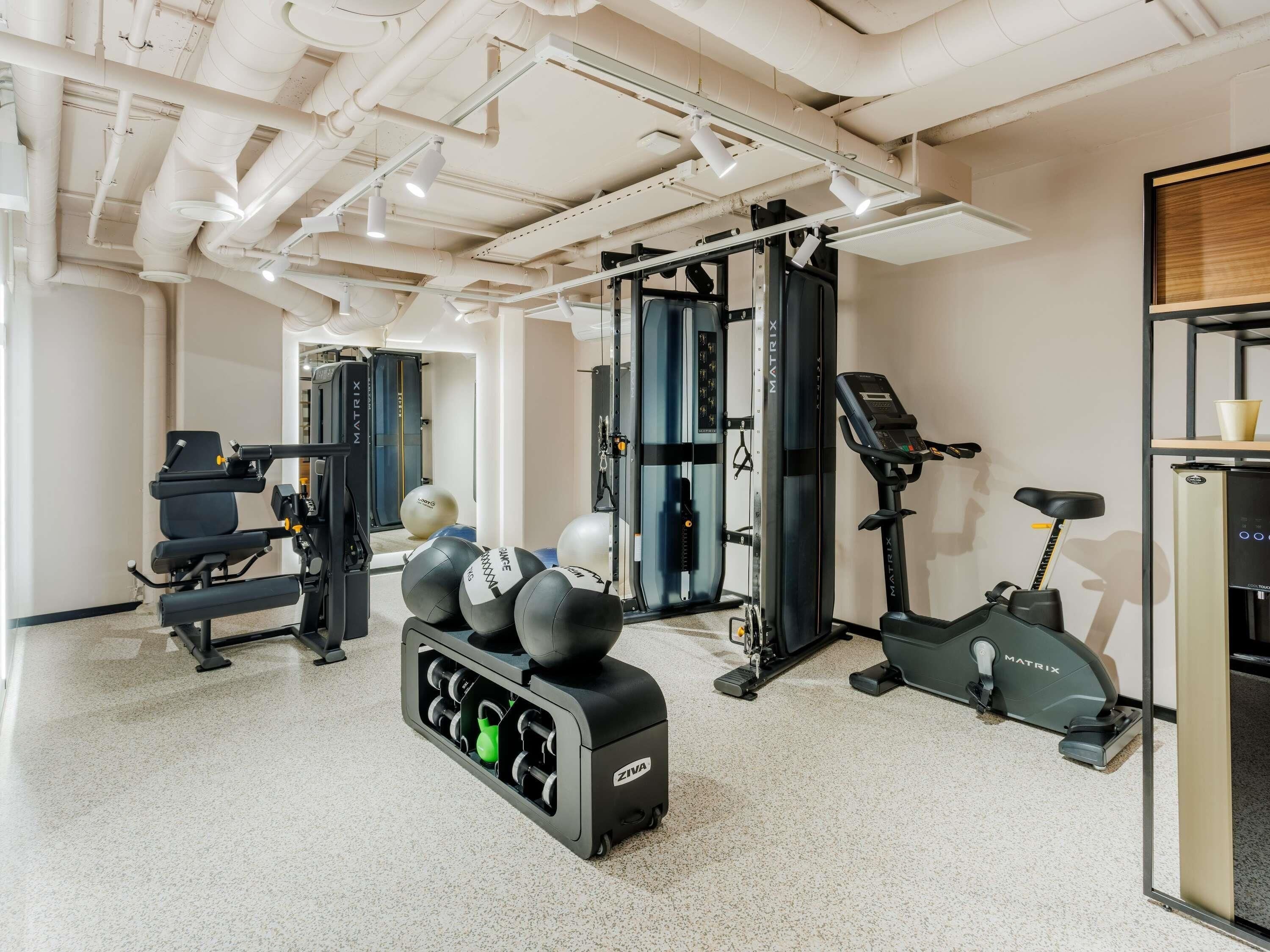 A gym with exercise equipment, a mirrored wall, and a treadmill.