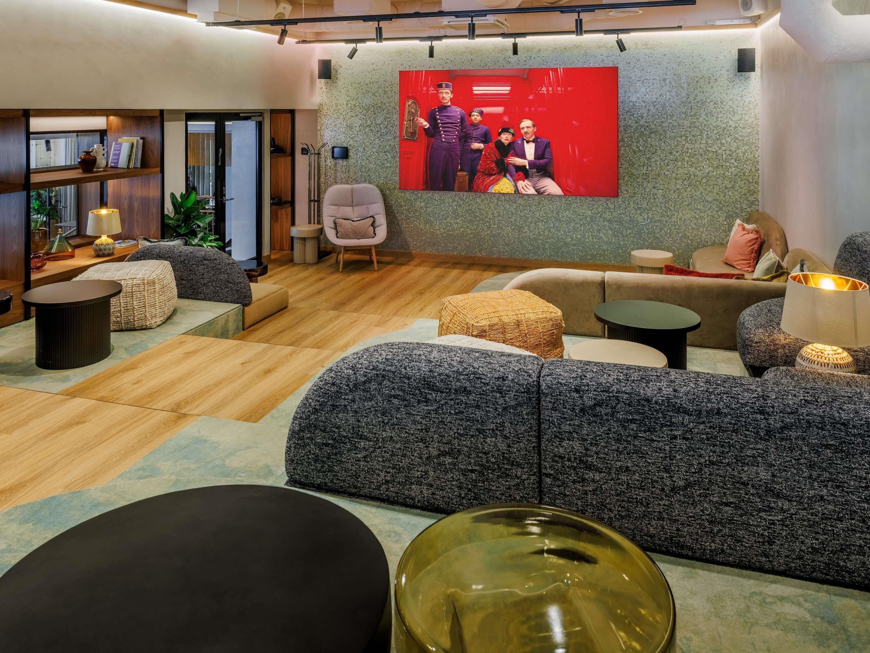 A modern living room with a sofa set, a coffee table, and a television mounted on a textured wall.