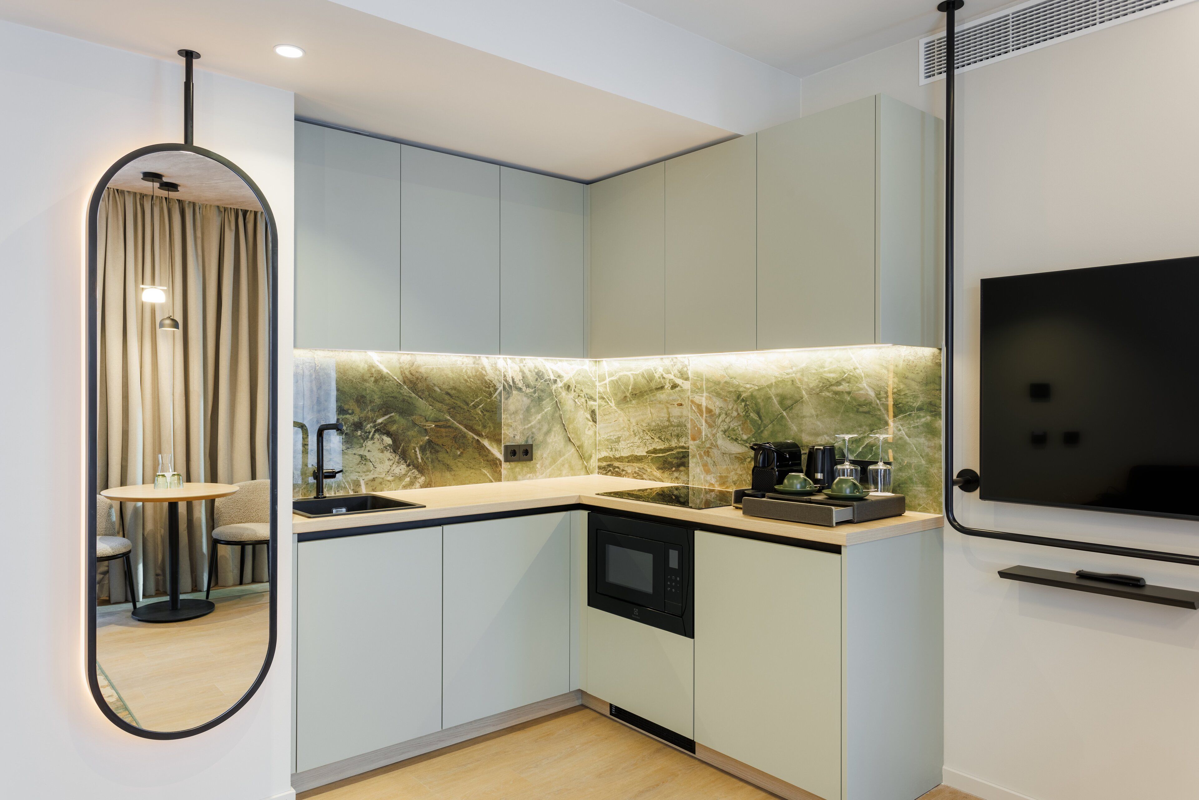 A modern kitchen with a built-in microwave, a coffee machine, and a large mirror.