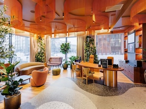 A modern interior with a round wooden desk, leather chairs, and large windows.