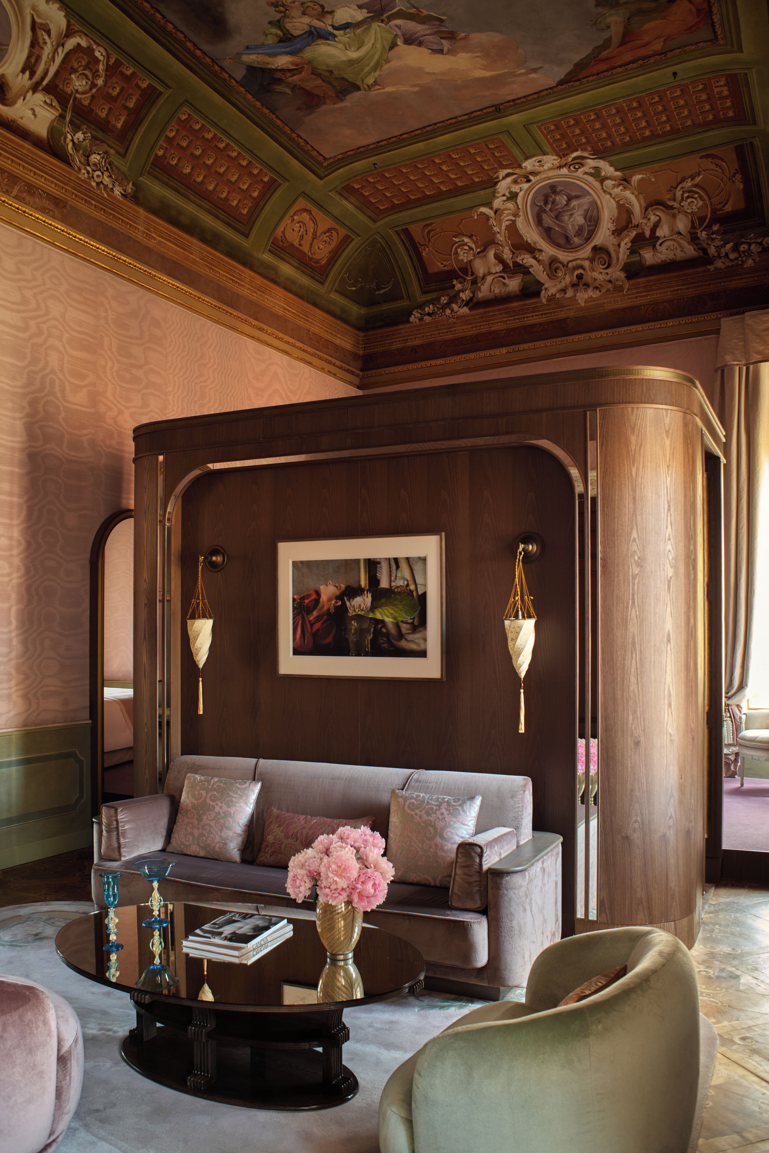 A room with a sofa, a coffee table, and a painting on the wall.