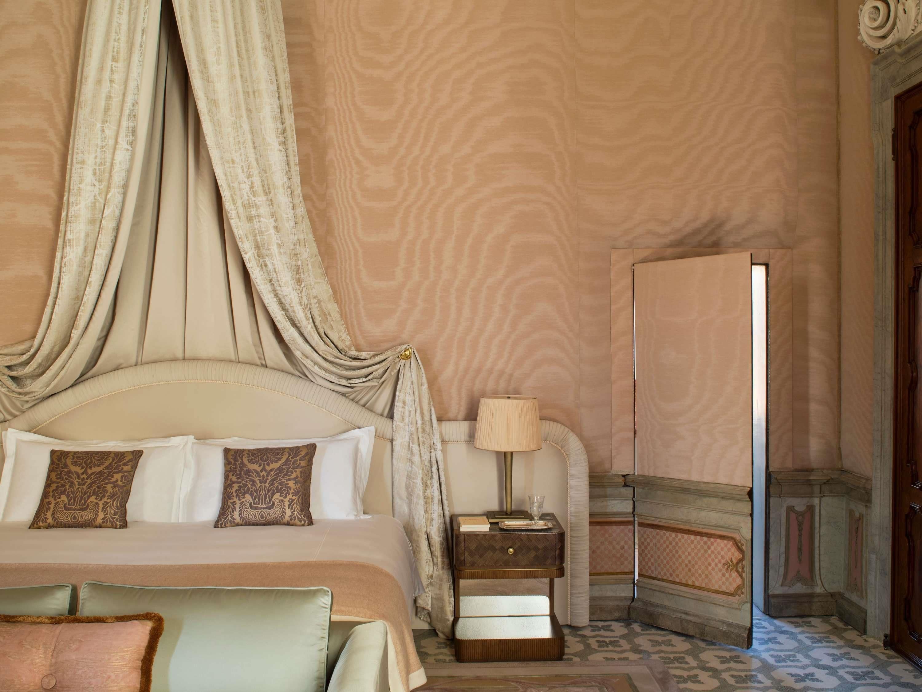 Une chambre à coucher avec un lit à baldaquin, une table de chevet avec une lampe et un miroir.