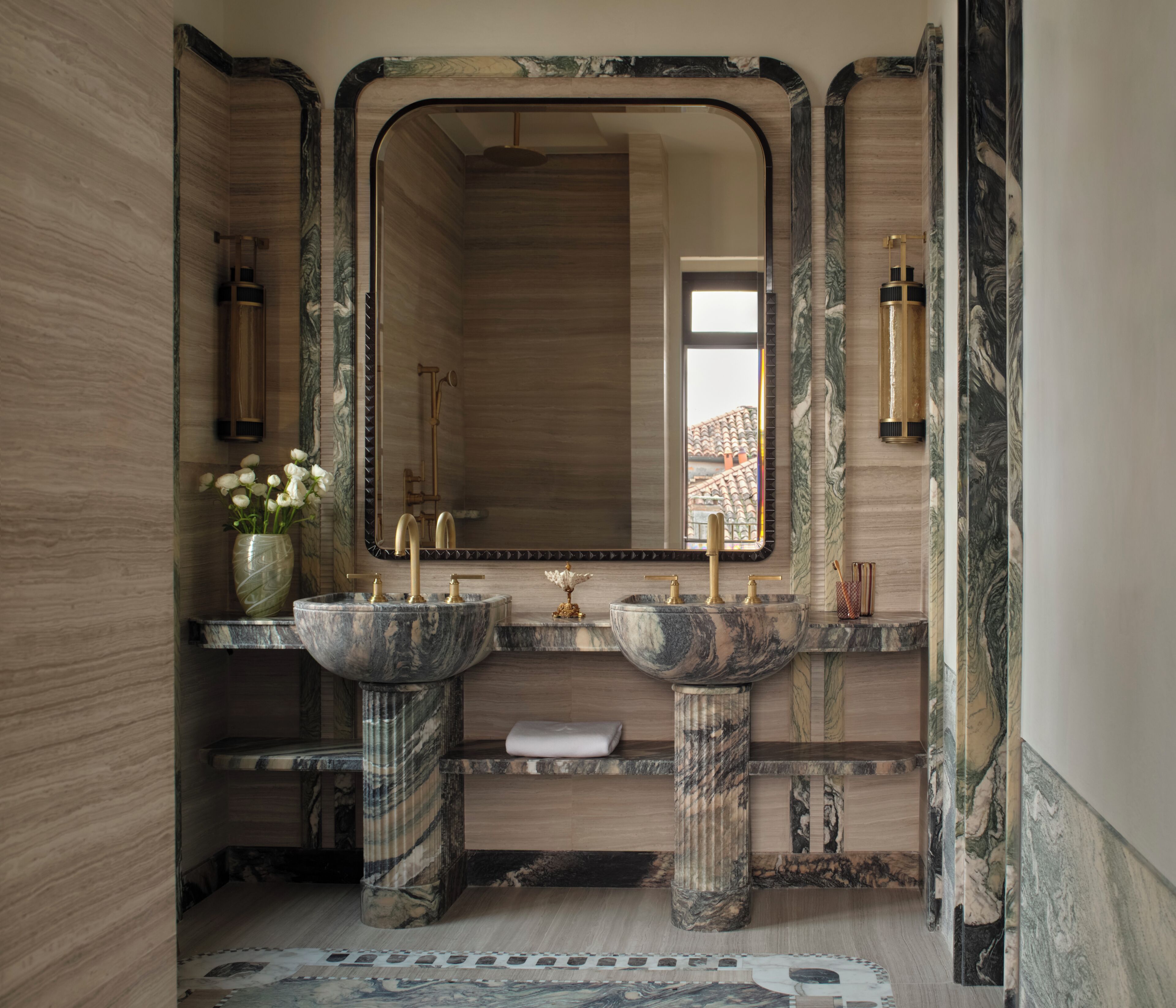 A bathroom with marble sinks, a large mirror, and a view of the outside.
