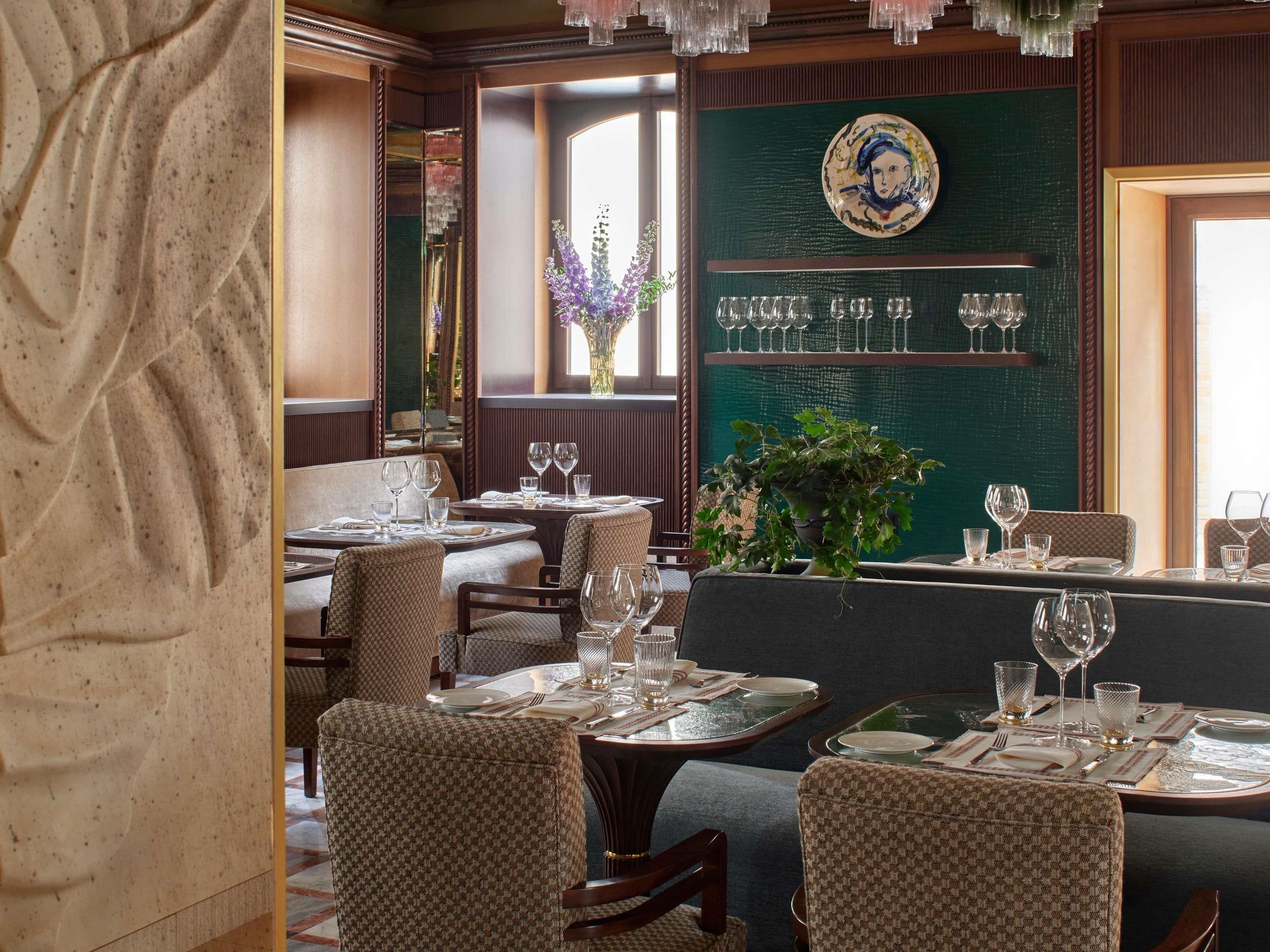 L’intérieur d’un restaurant, avec plusieurs tables, des chaises et un présentoir à vin fixé au mur.