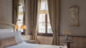 Une chambre d’hôtel avec un grand lit, un canapé, une petite table avec un vase et un grand miroir.
