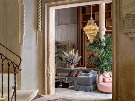 A grand lobby with a chandelier, sofas, a coffee table, and a staircase.