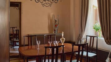 A dining area with a wooden table and chairs, a chandelier, and a vase with flowers.