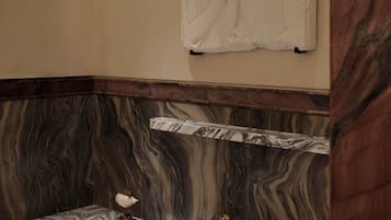 A bathroom with a marble sink, a gold faucet, and a marble wall.