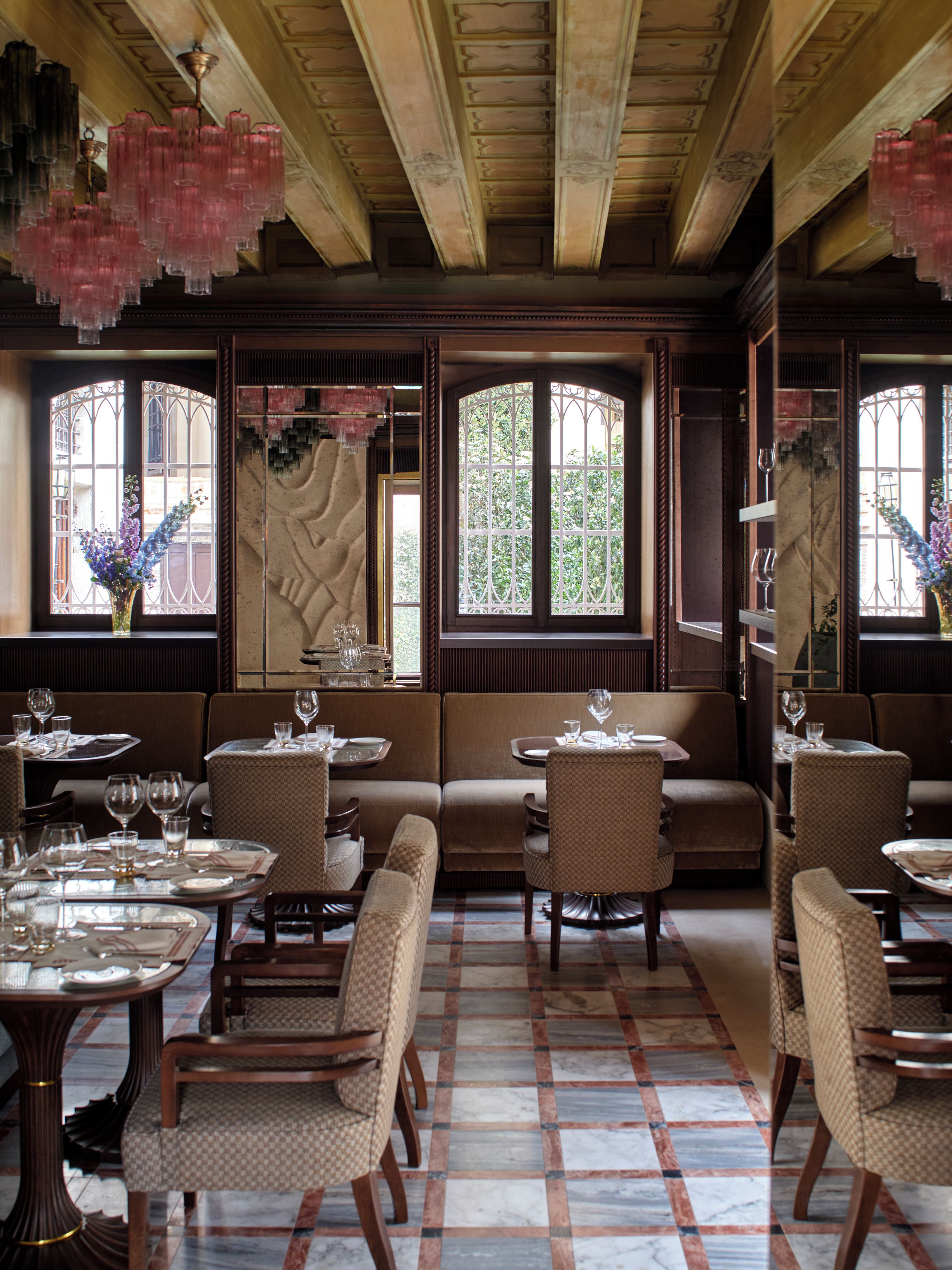A restaurant interior with wooden beams, patterned flooring, and seating arrangements.
