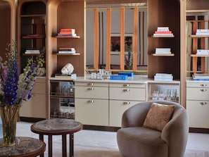 A modern interior with a round table, a sofa, and a bookshelf with books and decorative items. - Orient Express Venezia (Venice)