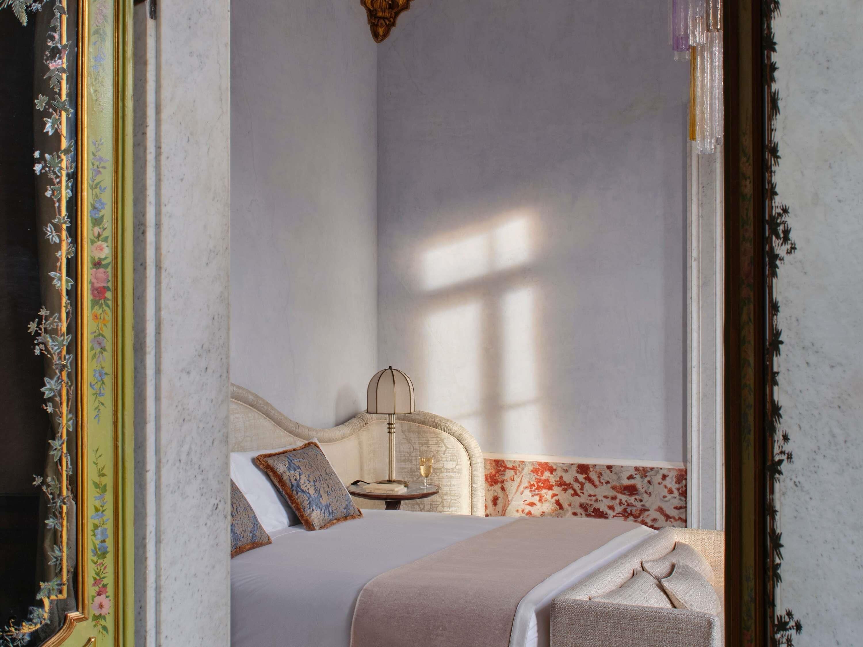 Une chambre à coucher avec un lit, des oreillers, une table de chevet avec une lampe et une fenêtre.