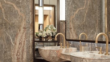 A bathroom with two marble sinks, a large mirror, and a dark cabinet.