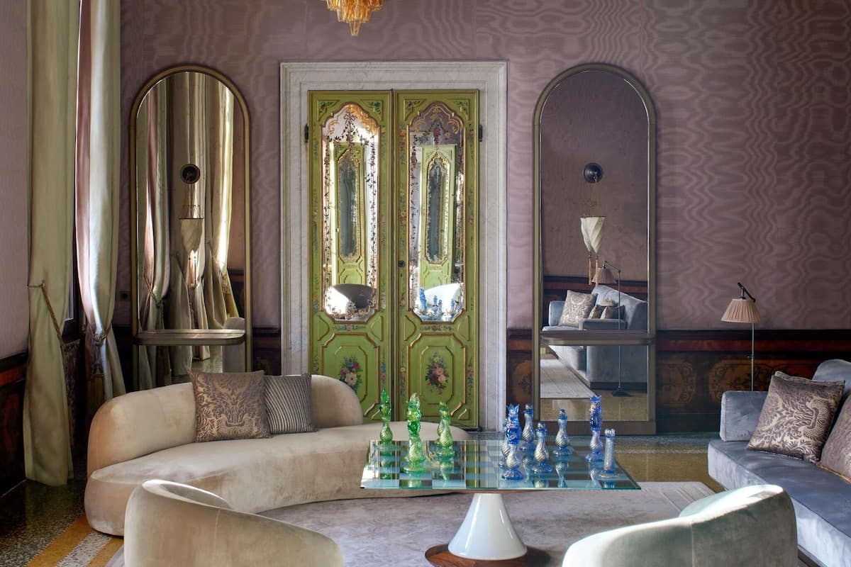 A room with a green door, a sofa, a chess table, and a chandelier.