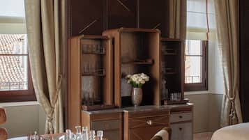 Une chambre d’hôtel comprenant un lit, un bureau avec une chaise, une coiffeuse avec un miroir, une commode et une fenêtre avec des rideaux.