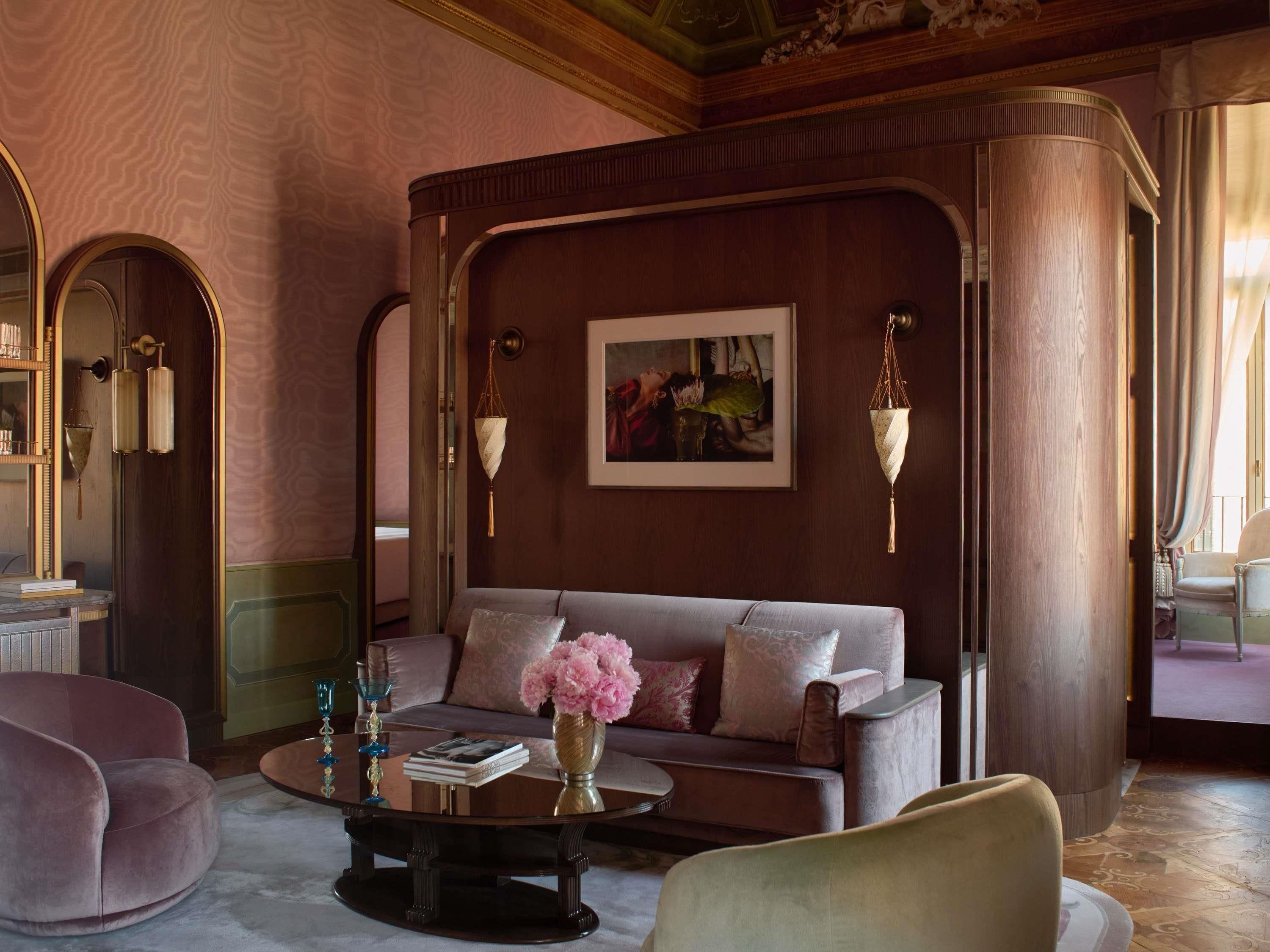 A luxurious living room with a sofa, a coffee table with a vase of flowers, and a painting on the wall.