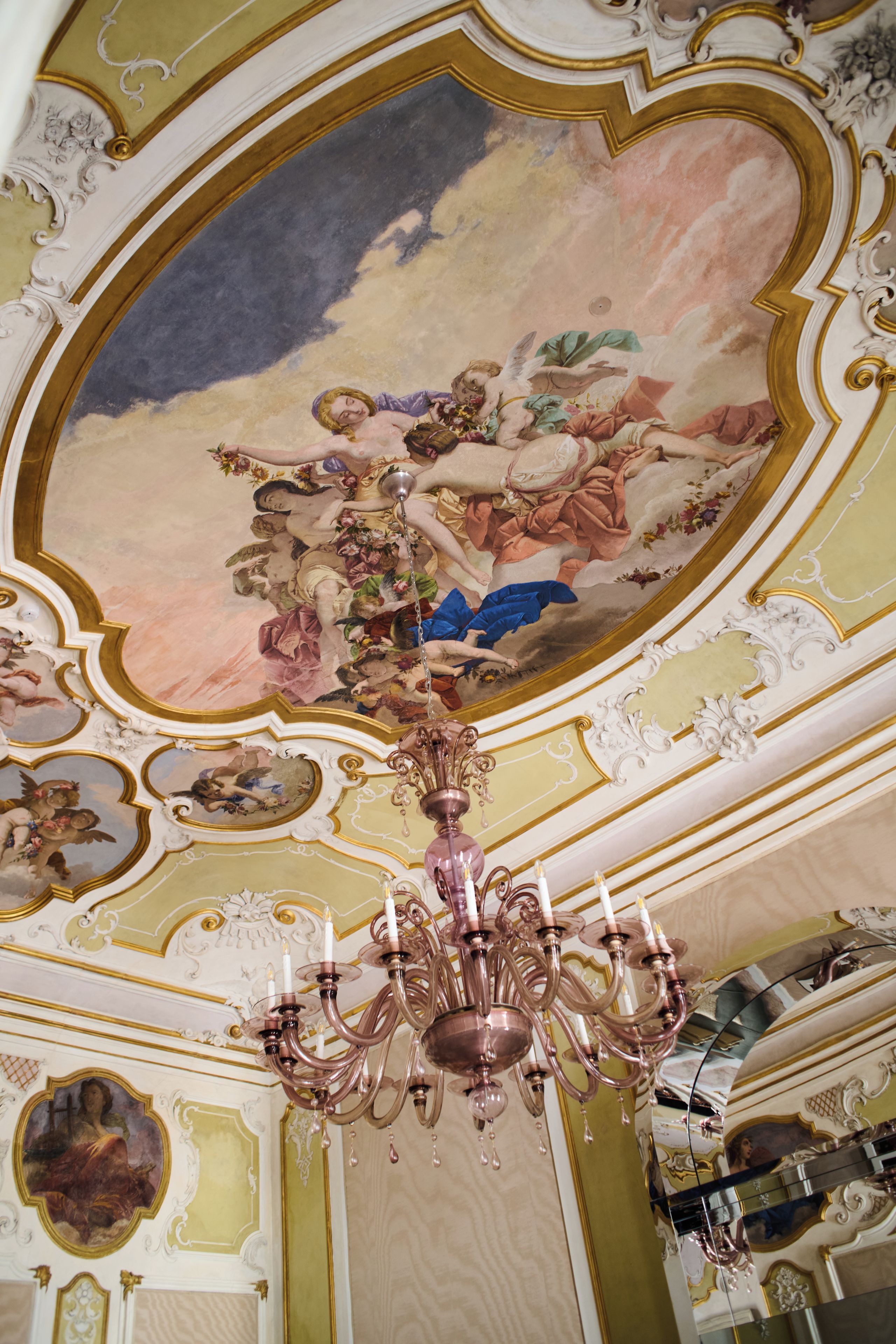 A ceiling with ornate gold detailing and a central fresco.