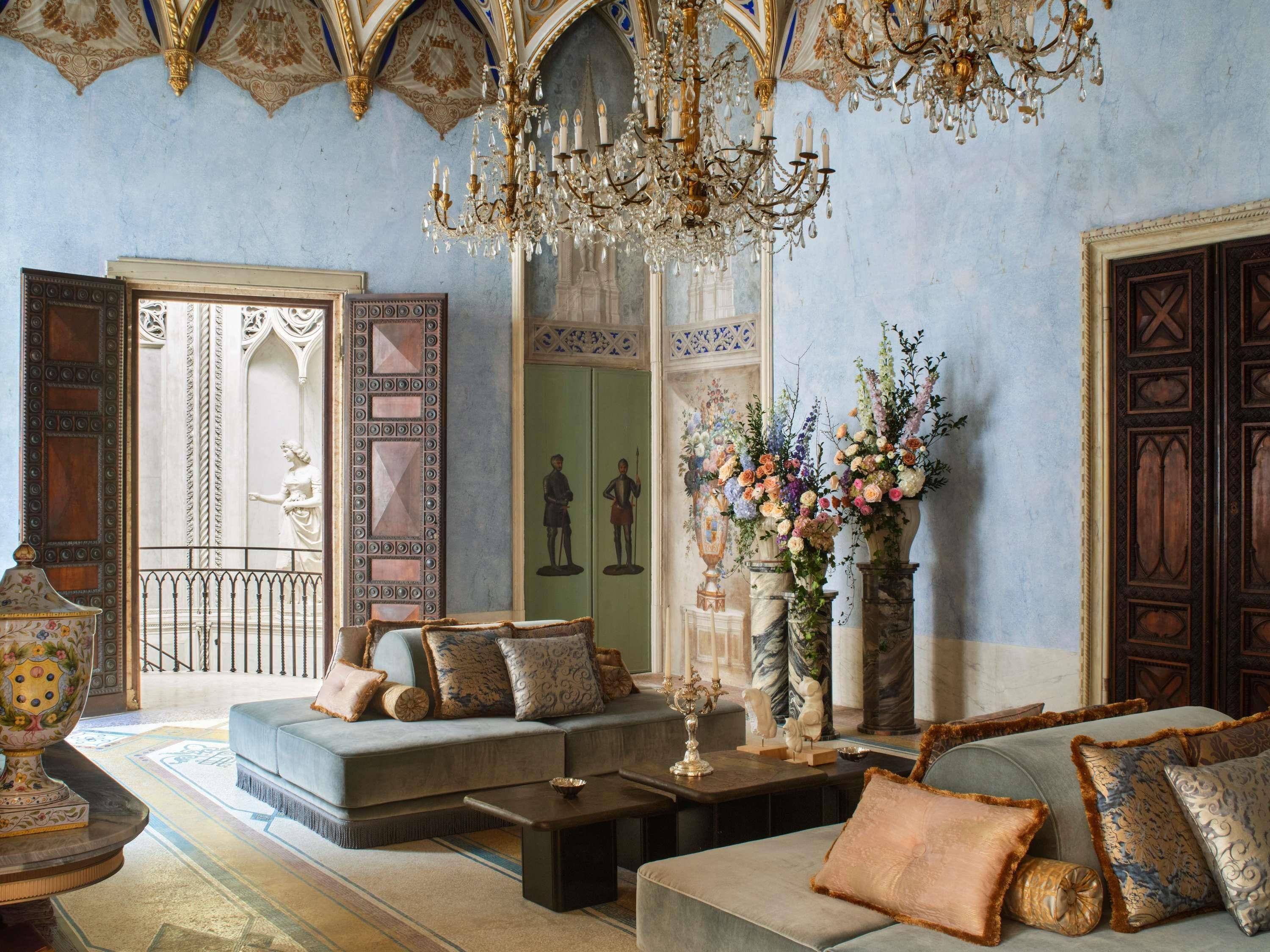 A luxurious room with a grand chandelier, ornate doors, and a plush sofa set.