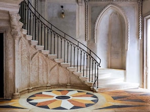 A grand staircase with ornate railings leading to a landing with a patterned floor. - Orient Express Venezia (Venice)