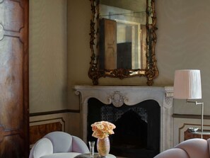 A room with a fireplace, a mirror, a vase with flowers, and a lamp. - Orient Express Venezia (Venice)