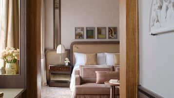Une chambre d’hôtel avec un lit, une table de chevet, une lampe, un vase de fleurs et un tableau encadré au mur.