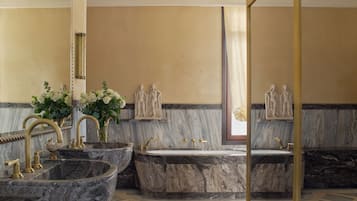 Un baño con lavamanos de mármol, bañera y esculturas en la pared.
