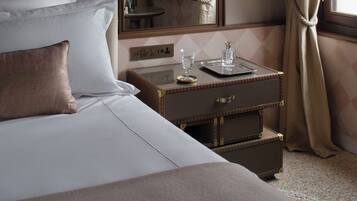 Una habitación de hotel con una cama, una mesita de noche con bandeja, un espejo y una lámpara colgante.