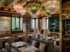 Un interior de restaurante con varias mesas, sillas y candelabros colgantes.