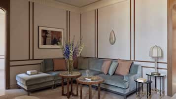 A modern living room with a sectional sofa, two round wooden tables, a floor lamp, and a framed picture on the wall.
