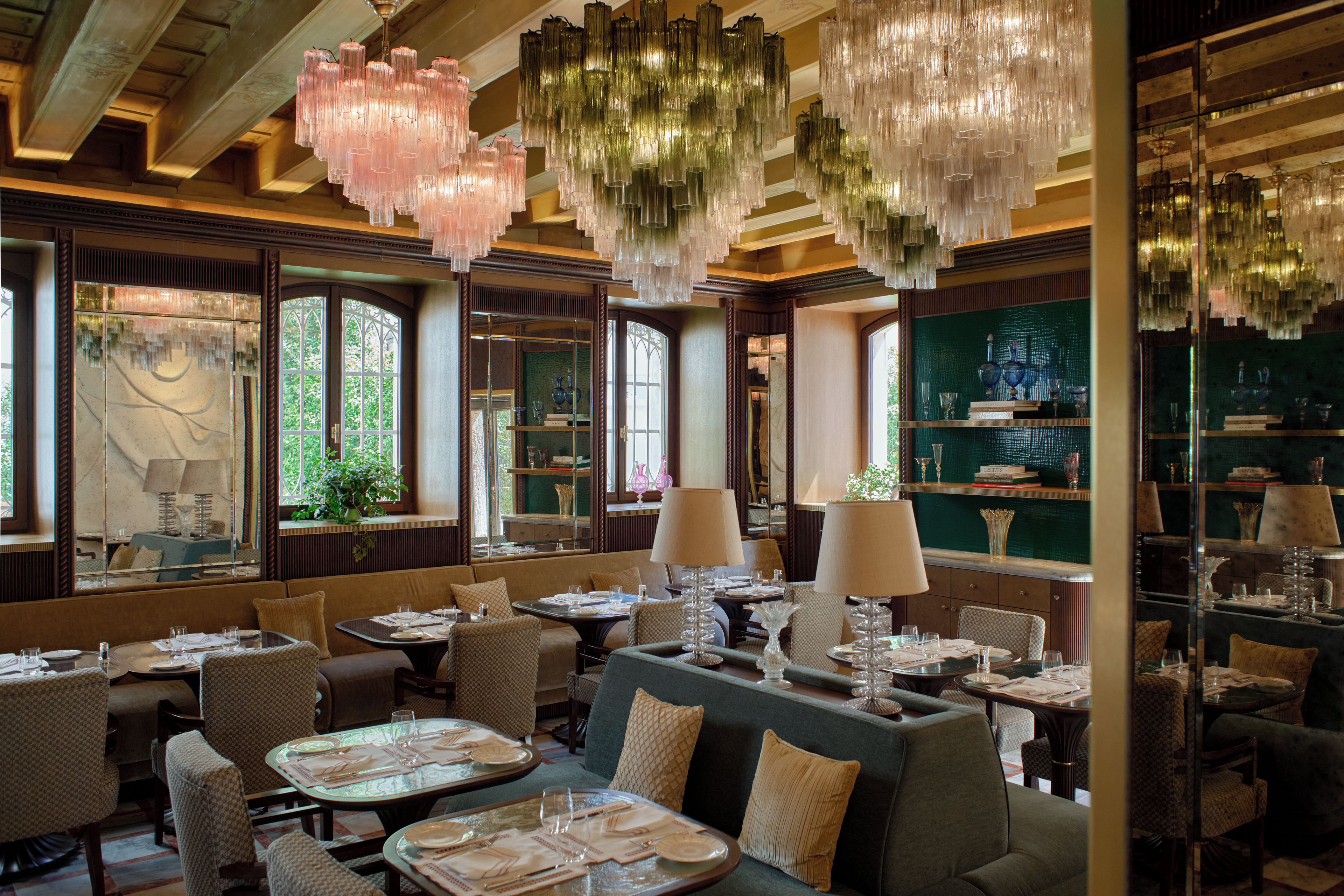 A restaurant interior with multiple dining tables, chairs, and hanging chandeliers.