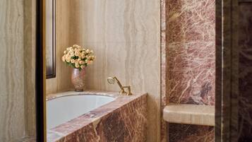A bathroom with a marble sink, a bathtub, and a shower area.