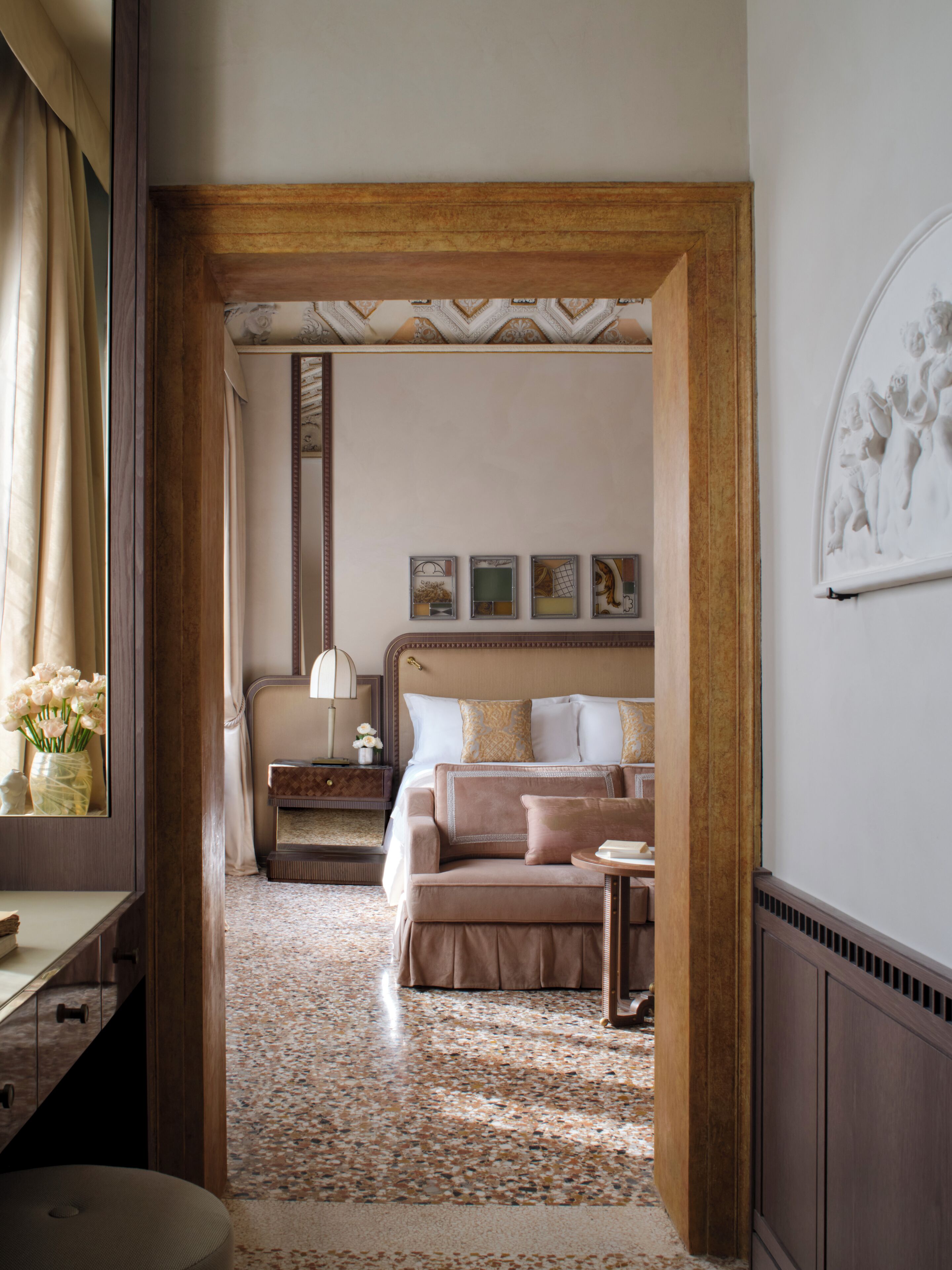 A hotel room with a bed, a nightstand, a chair, a desk, and a mirror.