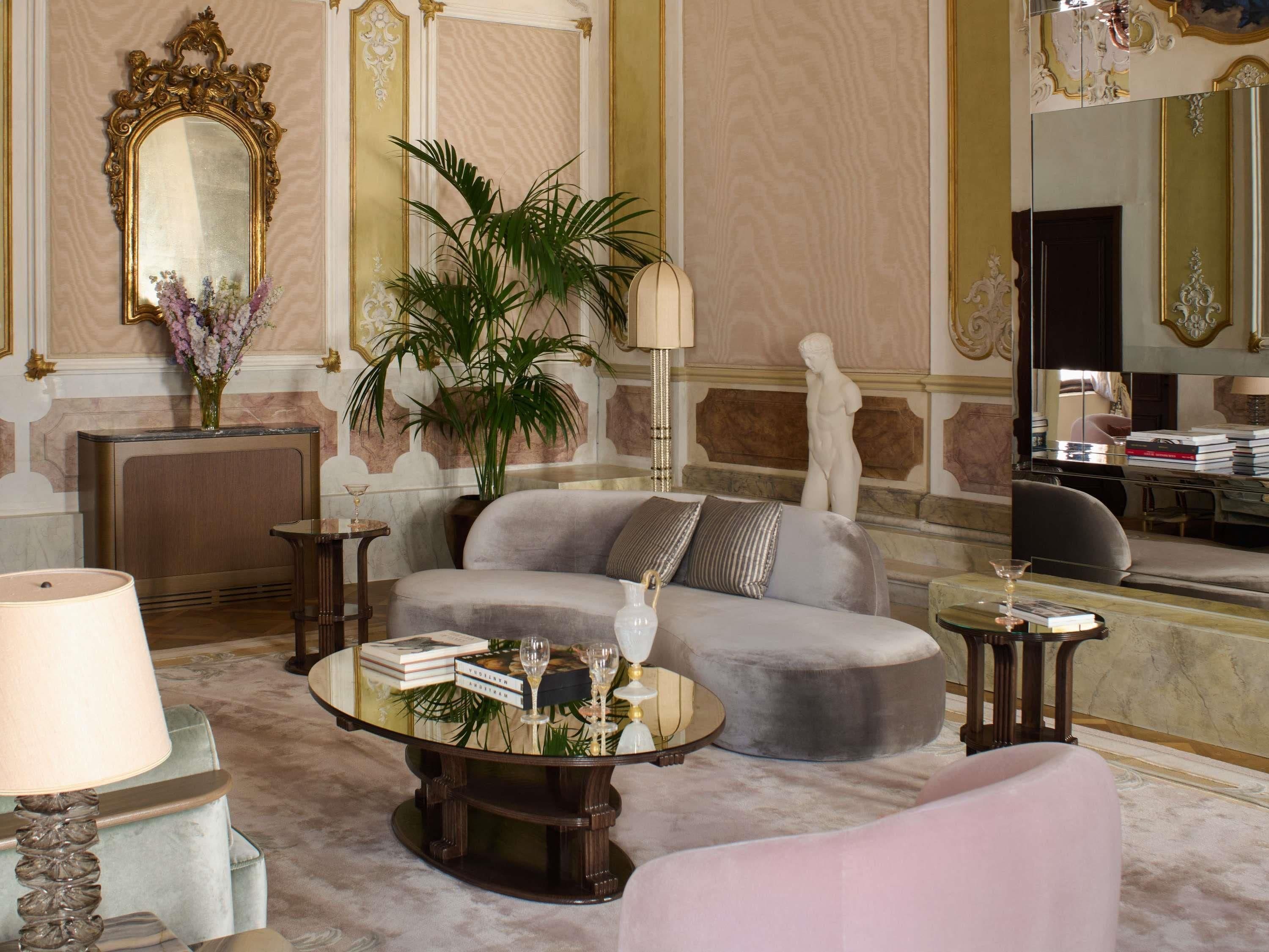 Un salon luxueux comprenant un canapé, une table basse, une lampe, une plante et une statue.