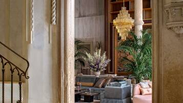 A grand lobby with a chandelier, sofas, a coffee table, and a staircase.
