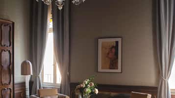 Una habitación con dos sofás, una araña, una obra de arte enmarcada y un jarrón con flores.