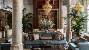 A luxurious lobby with a blue sofa, large columns, a grand chandelier, and a large mural. - Orient Express Venezia (Venice)