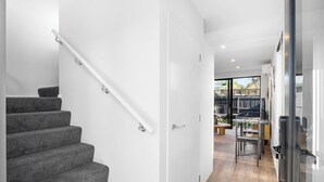 Een modern interieur met een trap, een glazen deur naar een balkon en een keukenhoek.