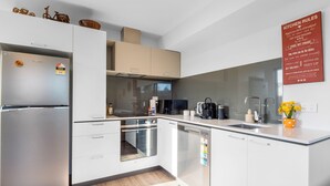 Een moderne keuken met witte kastjes, roestvrijstalen apparatuur en een houten vloer.